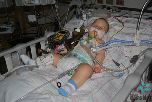 A baby in a hospital bed hooked up to many tubes and wires. Logo: Houston moms Blog. 