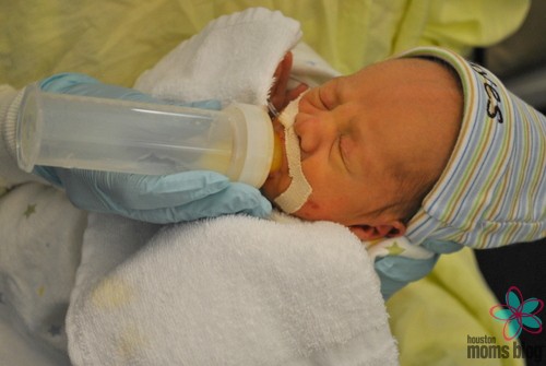 A baby in the NICU being given a bottle. Logo: Houston moms Blog. 