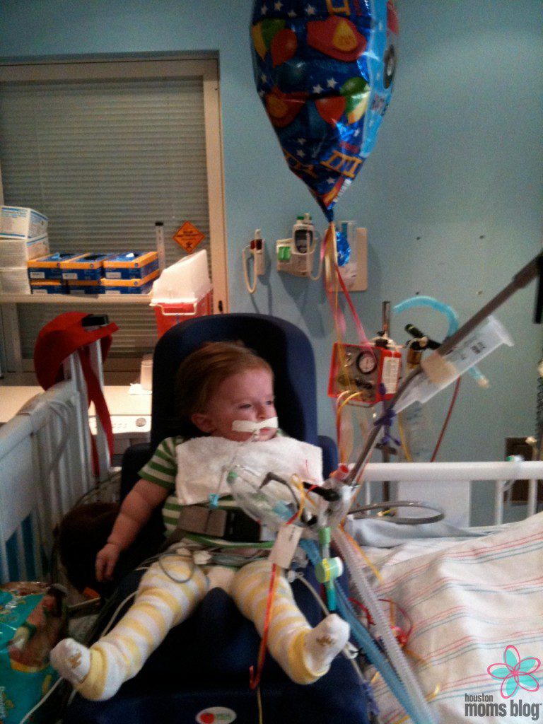 A young child sitting on a chair in a hospital connected to tubes and wires. Logo: Houston moms blog.