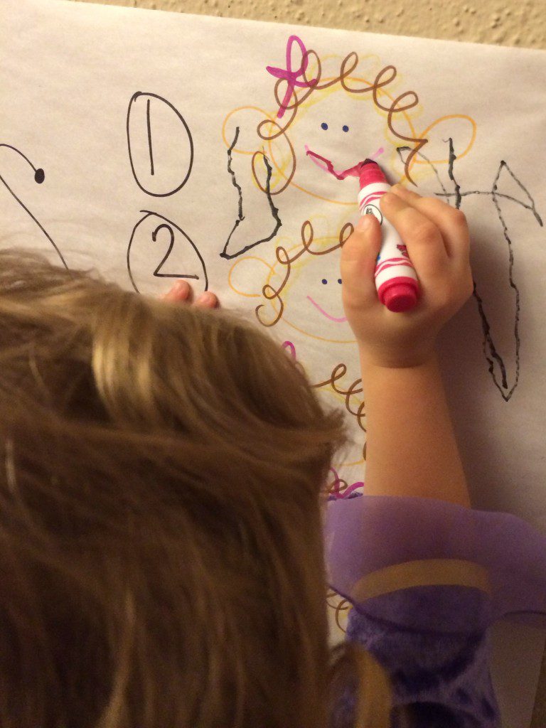 A young child drawing on the previously described drawing. 