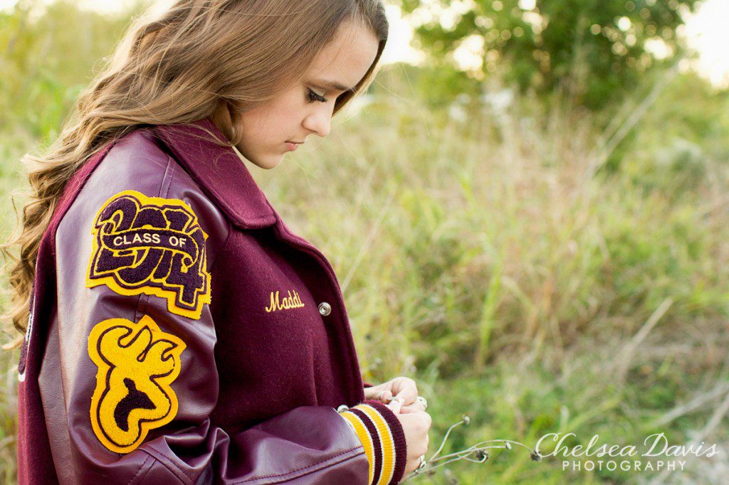 A teenage girl wearing a high school jacket. Logo: Chelsea Davis Photography. 