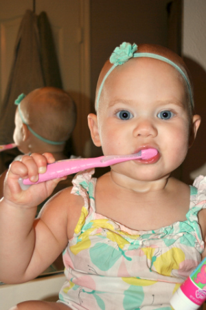 A toddler bushing her teeth. 
