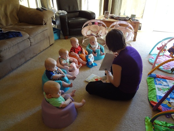 A woman reading to five babies.