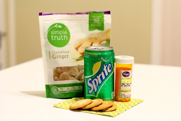 A photograph of a package of crystallized ginger, a sprite, crackers and a bottle of medicine.