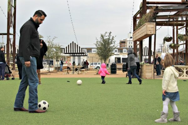 A father and daughter playing soccer outside. 