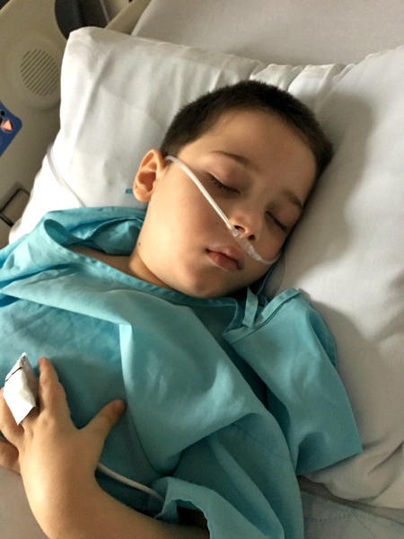 A child lying in a hospital bed with a nasal canula in. 