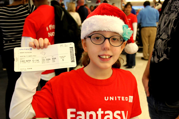 A child wearing a santa hat and holding a Flight ticket. 