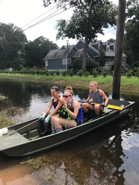 Three teenage girls in a canoe on a narrow river. 