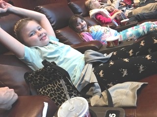 Children sitting in reclining chairs at a movie.