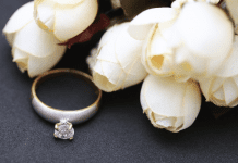 Fabric white roses next to a diamond ring.