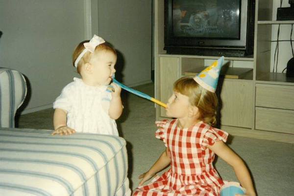 A child and a toddler playing with party favors. 