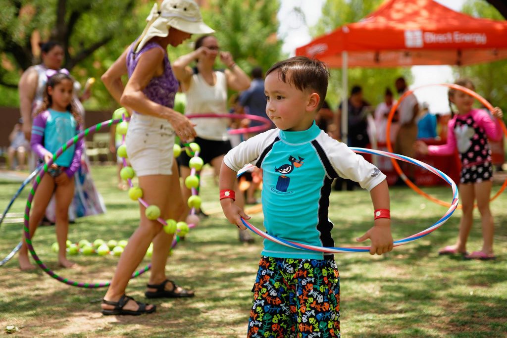 A group of children playing with hula-hoops in a park. 