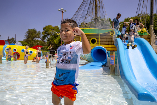 A child posing in front of a water slide at New Braunfels Water Park.