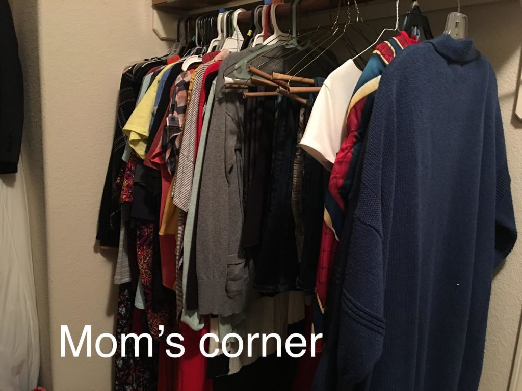 Clothes hanging in a closet labeled Mom's corner. 