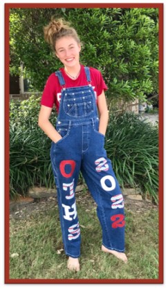 A teenage girl wearing overalls. One pants leg contains the text O T H S. The other contains the text 2022. 