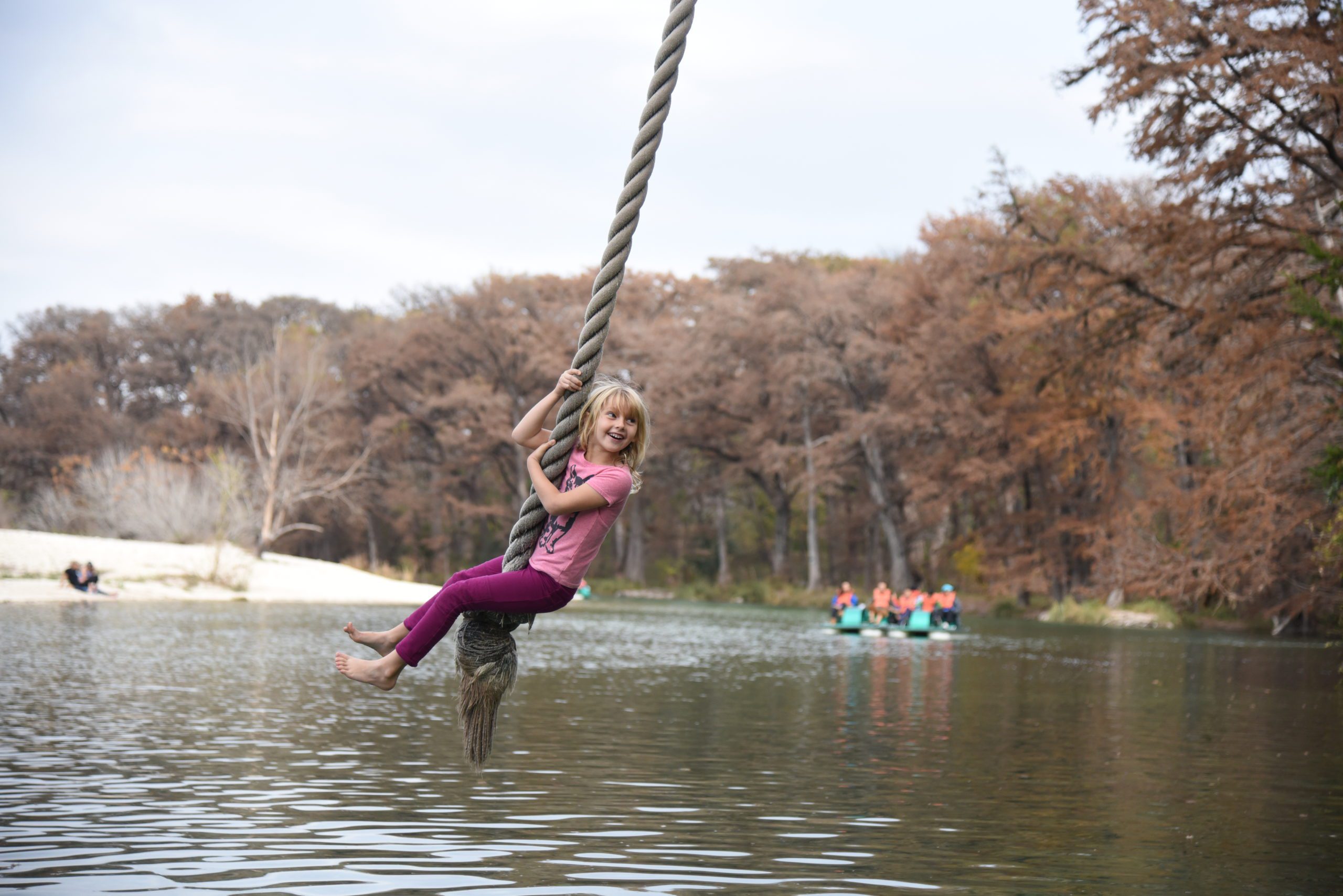 child swinging on rope over a river