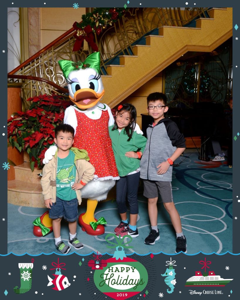 A Disney Cruise Line Happy Holidays card with three children posing with Daffy Duck. 