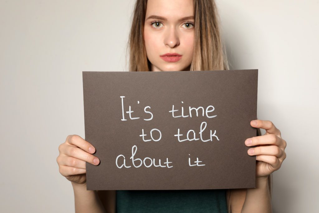 A woman holding a sign with the text: It's time to talk about it. 