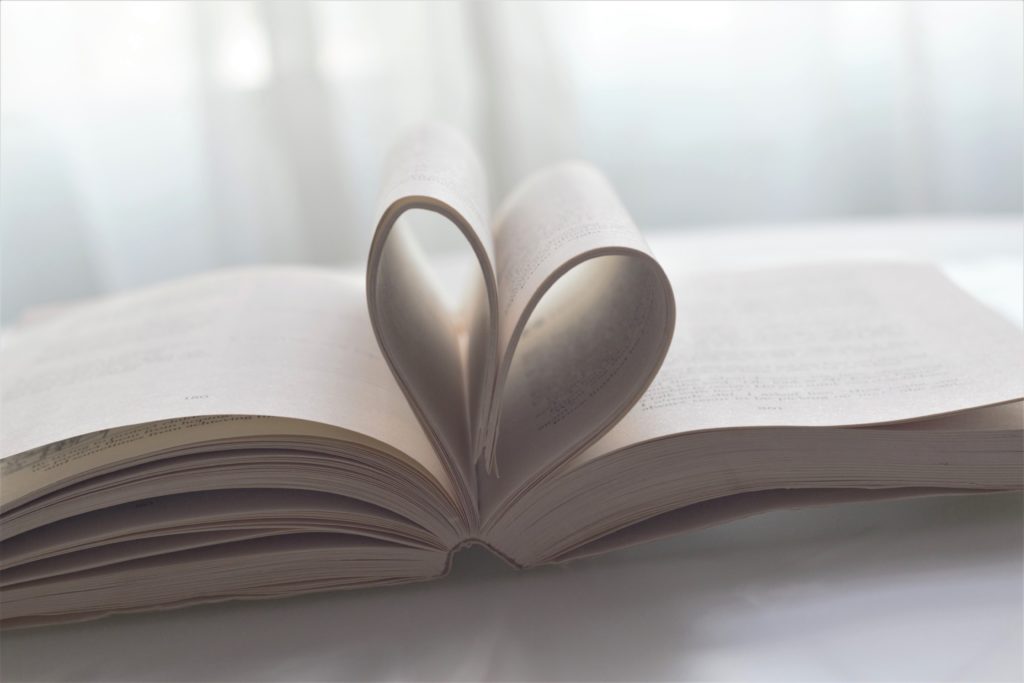 An open book with the pages folded in the shape of a heart. 