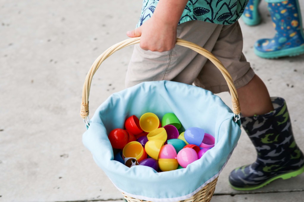 A child carrying a basket filled with open plastic eggs. 