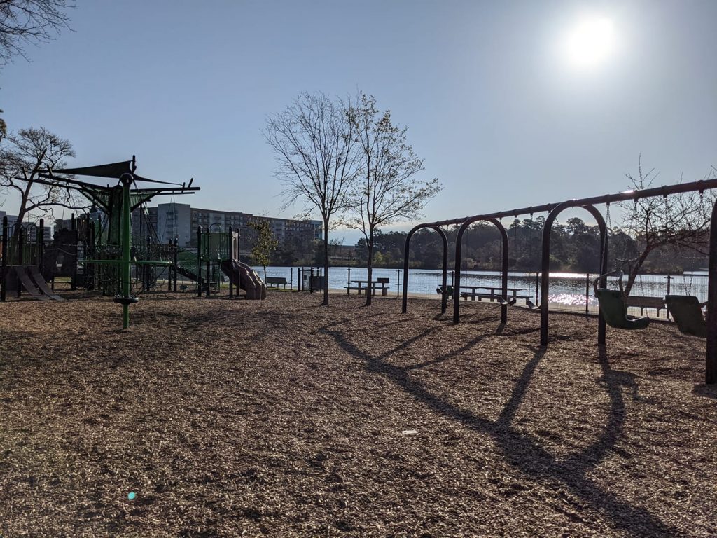 A playground next to a lake. 