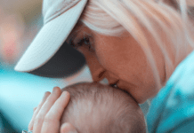 A woman kisses a baby's head.