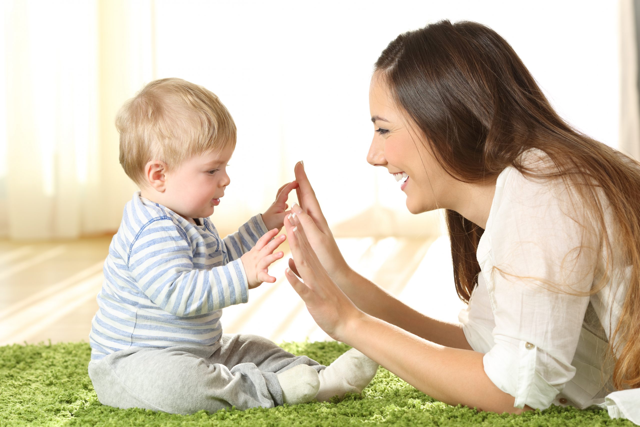 A mother clapping hands with a small child. 