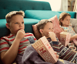 Three children holding cartons of popcorn. 