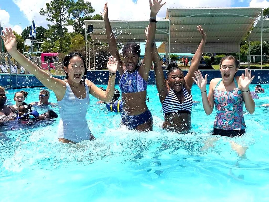 Four teenage girls jumping in a pool at Moody Gardens. 