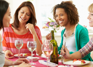 Four smiling women eating a meal together.
