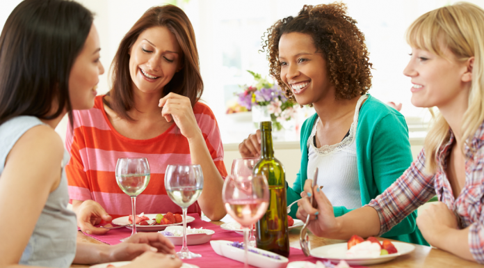 Four smiling women eating a meal together.