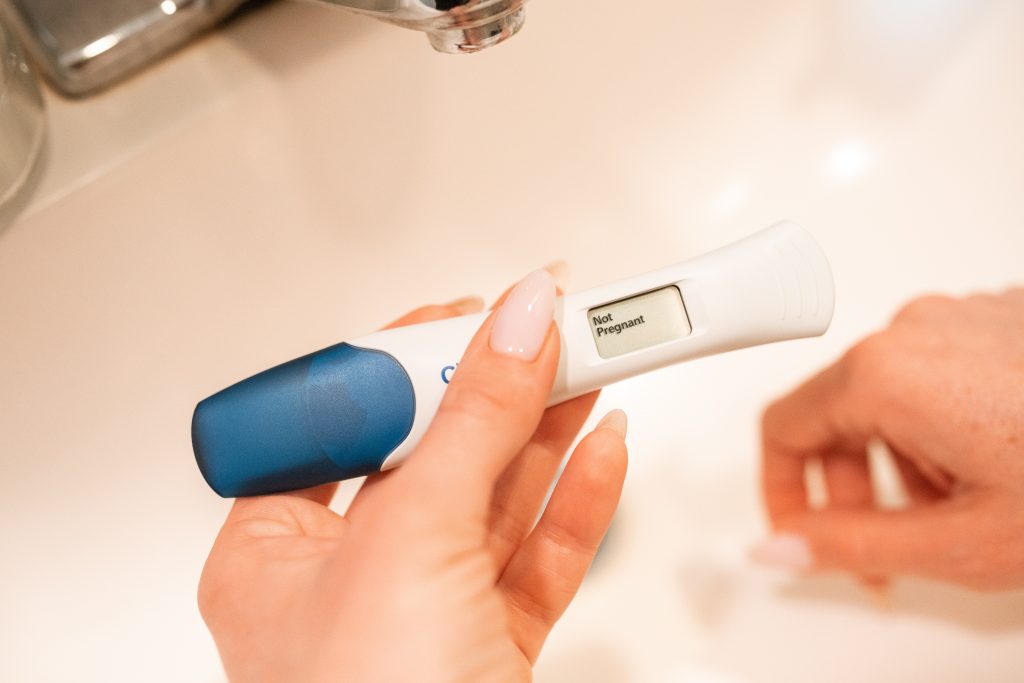 A woman holding a pregnancy test displaying the text Not Pregnant. 