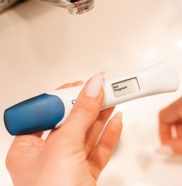A woman holding a pregnancy test displaying the text Not Pregnant.