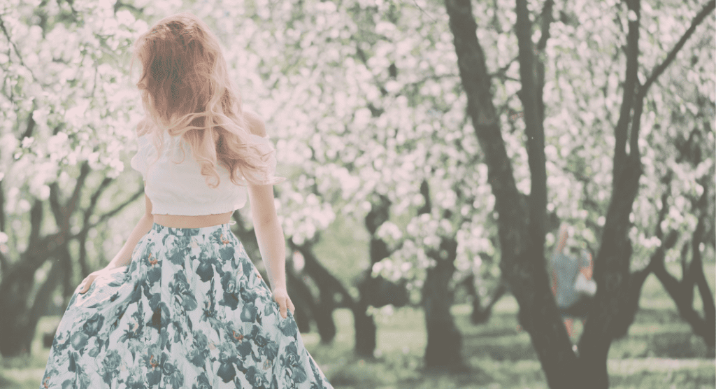 A woman in a grove of flowering trees. 