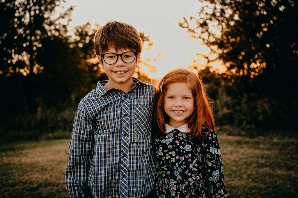 Brother in plaid and sister in floral pose for family photos