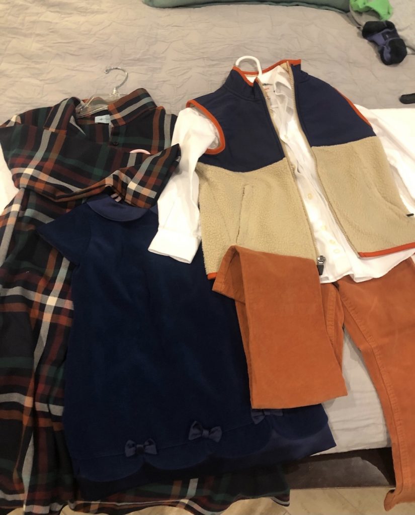 Stack of outfits laying on bed for family photos