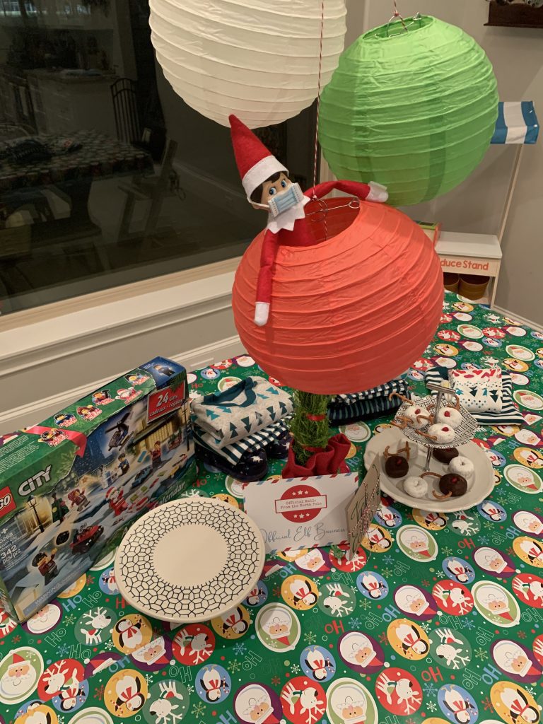 Elf on the Shelf with a mask on hanging from paper lanterns