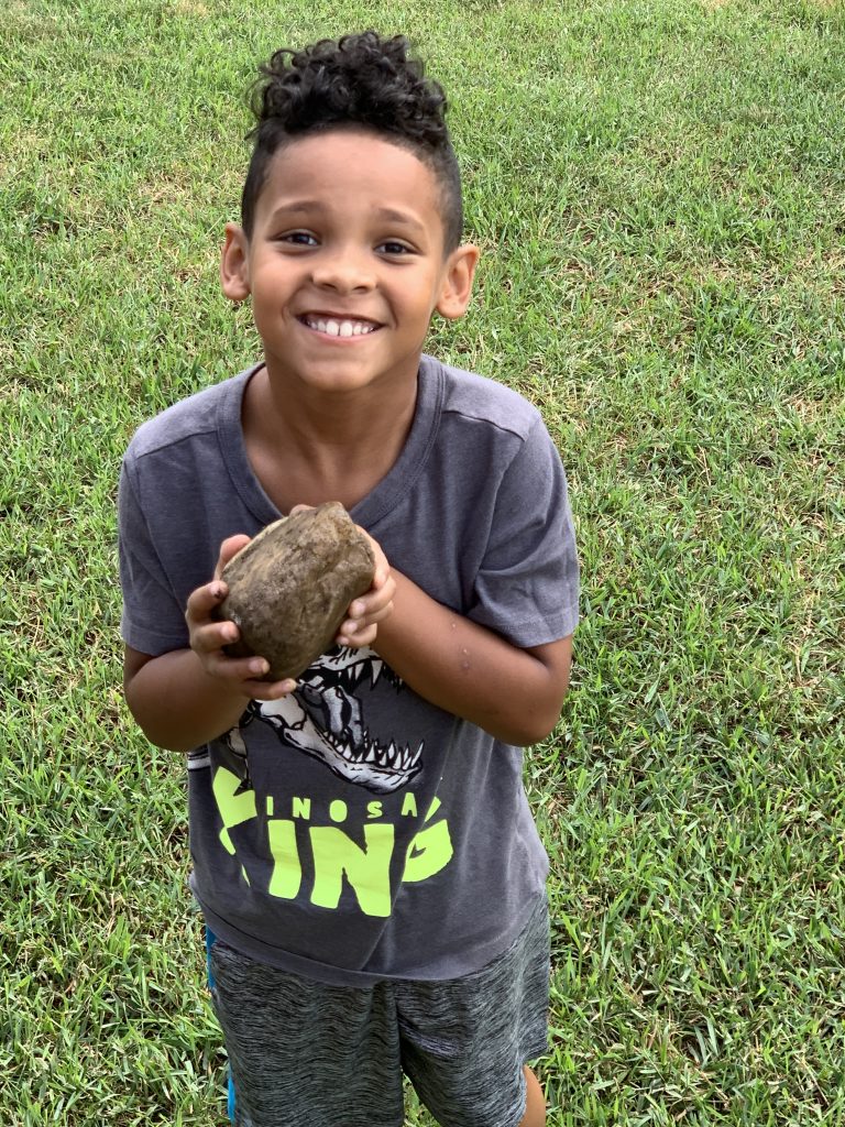 child holding a rock smiling at camera