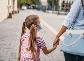 working mom holding daughters hand as they walk to school