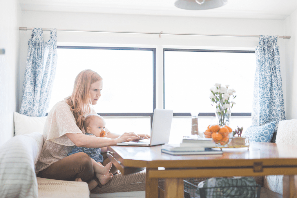 woman with baby on lap logging on to Facebook moms groups