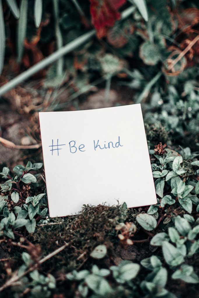 note with #Be Kind laying in patch of foliage