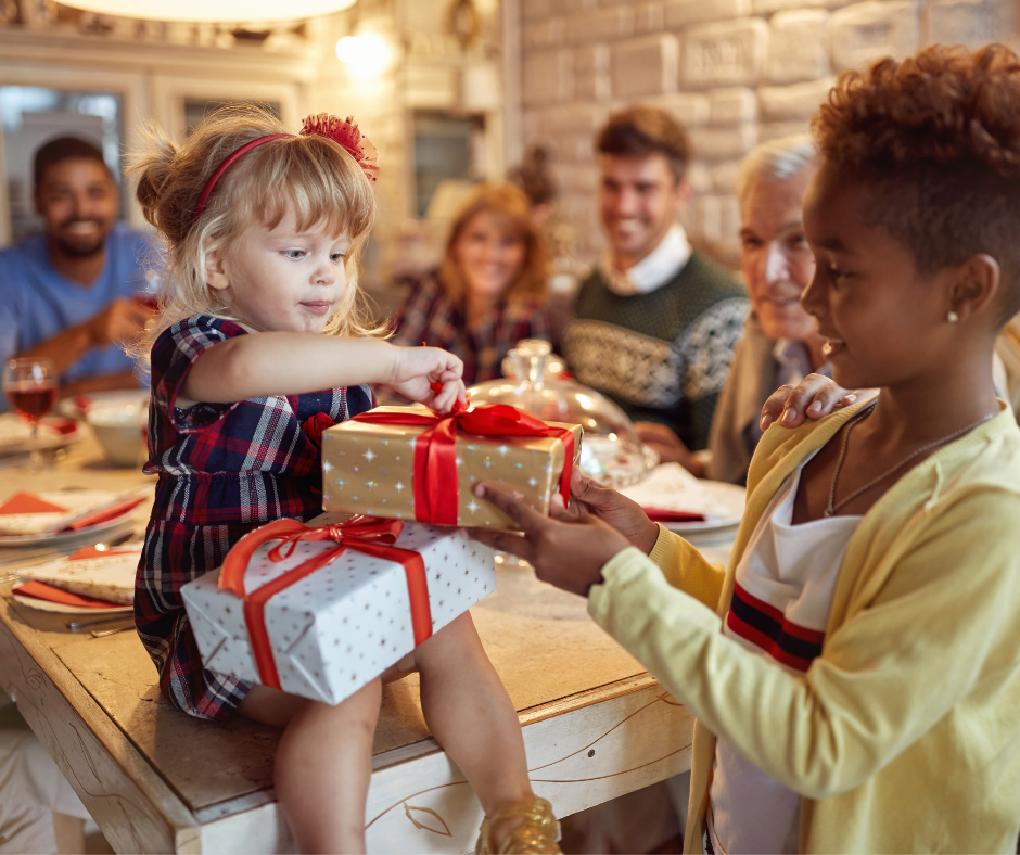 little girl helps toddler open Christmas gift