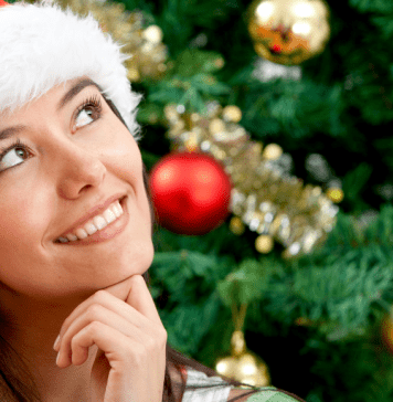 woman with Santa hat smiling thoughtfully