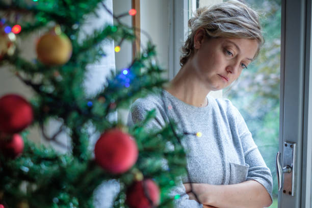 Sad woman standing beside Christmas tree