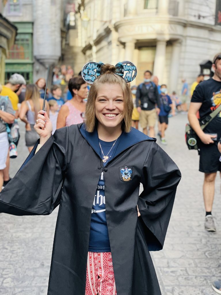 the author at Harry Potter World, holding a wand and wearing mouse ears