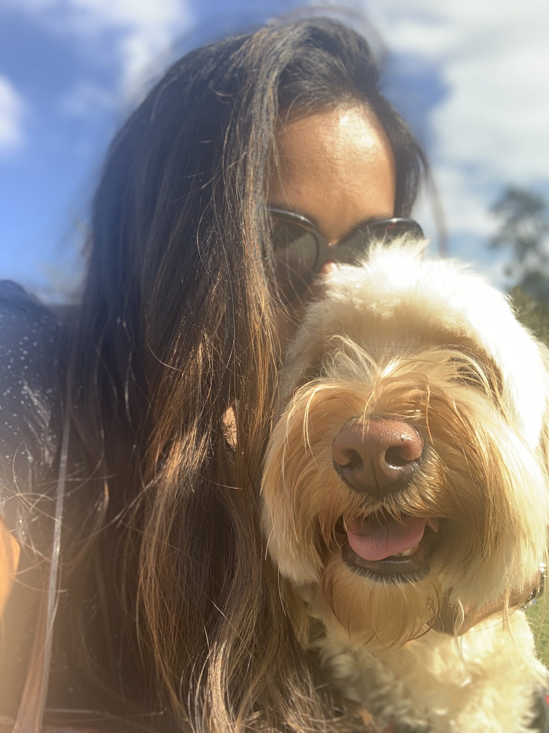 woman with sunglasses poses outside with dog