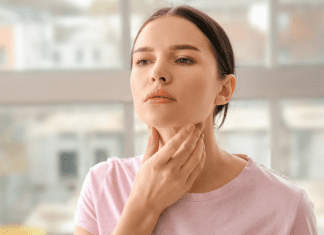 woman touching her neck where her thyroid is located