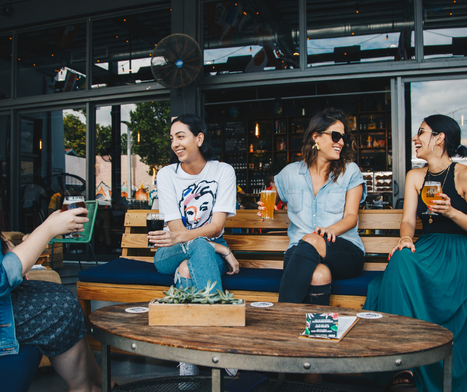 women sit on outside restaurant patio drinking beer