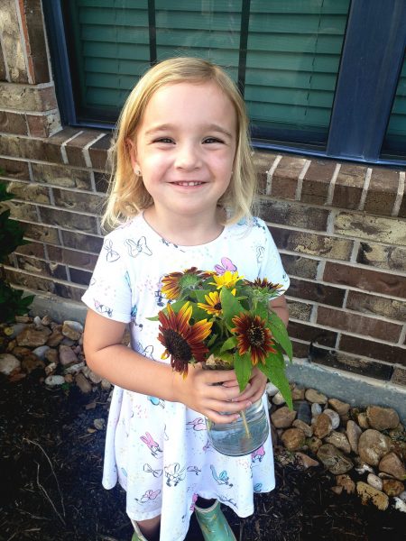 4 year old girl holding bouquet of sunflowers