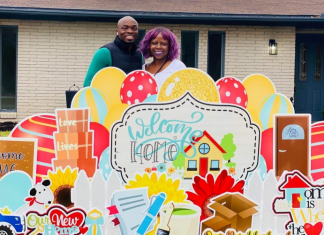couple who are buying a house stand in front of their home with celebratory yard signs